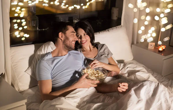 Pareja con palomitas de maíz viendo la televisión por la noche en casa —  Fotos de Stock