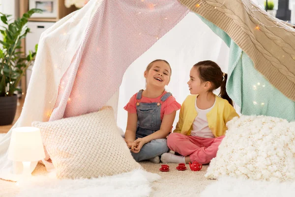 Маленькая девочка играет чаепитие в детской палатке дома — стоковое фото