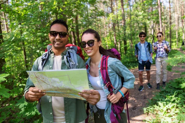 Amigos com mapa e mochilas caminhadas na floresta — Fotografia de Stock