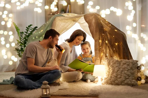 Happy family reading book in kids tent at home — Stock Photo, Image
