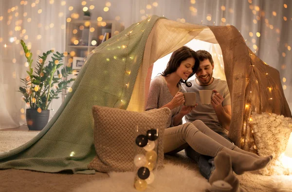 Пара пьет кофе или чай в детской палатке дома — стоковое фото