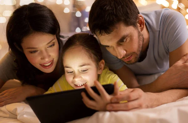 Familia con tableta pc en la cama por la noche en casa —  Fotos de Stock