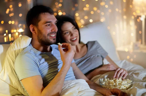Пара з попкорном дивиться телевізор вночі вдома — стокове фото