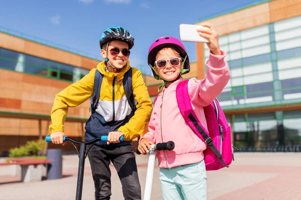 Niños felices de la escuela con scooters tomando selfie —  Fotos de Stock