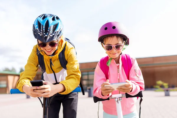 Crianças da escola com smartphones e scooters — Fotografia de Stock