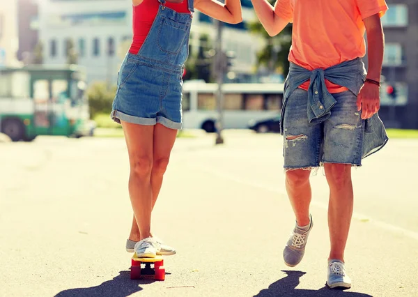 Teenage couple riding skateboard on city street — Stock Photo, Image