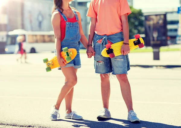 Primer plano de pareja joven con patinetas en la ciudad — Foto de Stock