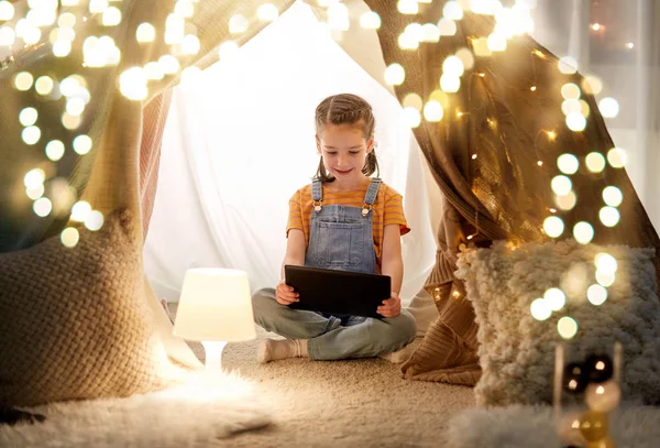 Bambina con tablet pc in tenda per bambini a casa — Foto Stock