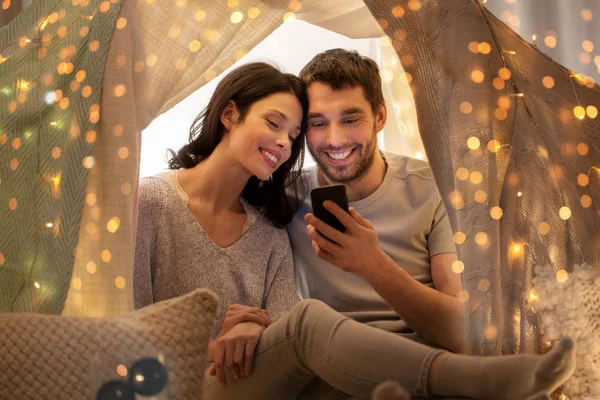 Feliz pareja con smartphone en tienda de campaña para niños en casa — Foto de Stock