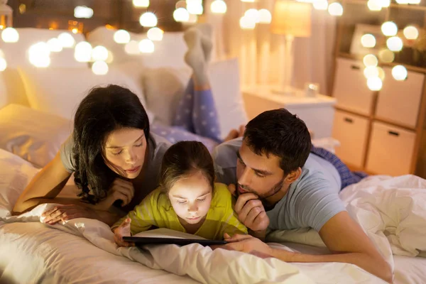 Familj med TabletPC i sängen på natten hemma — Stockfoto