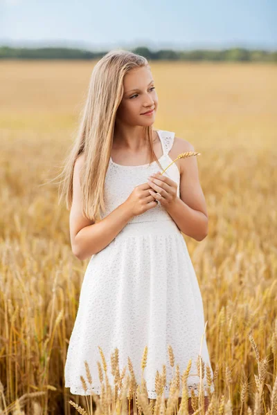 Niña con espiguilla de trigo en el campo de cereales — Foto de Stock