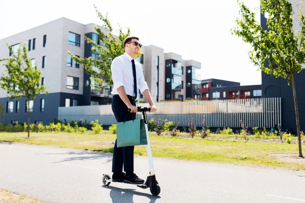 Zakenman met boodschappentas rijden scooter — Stockfoto