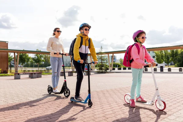 Niños de la escuela feliz con la madre que monta scooters —  Fotos de Stock