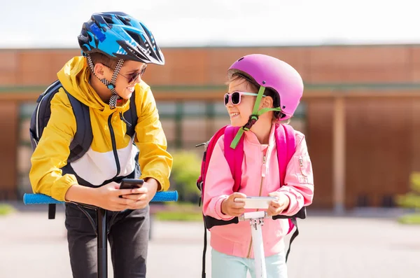 Crianças da escola com smartphones e scooters — Fotografia de Stock