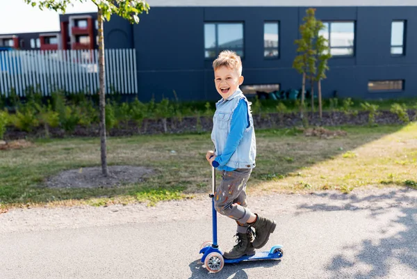 Gelukkig jongetje paardrijden scooter in stad — Stockfoto