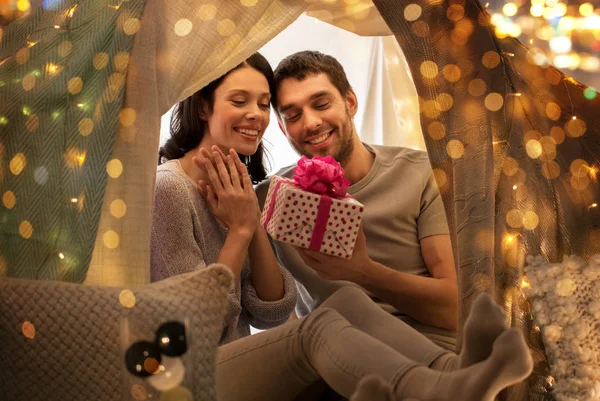 Счастливая пара с подарочной коробкой в детской палатке дома — стоковое фото
