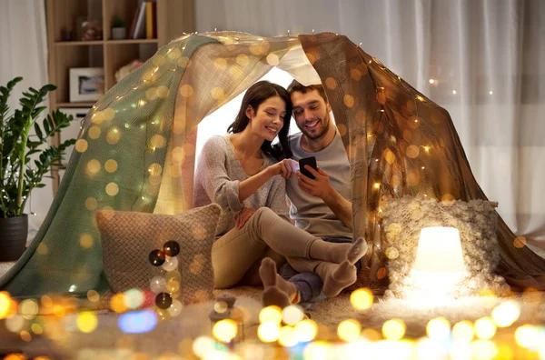 Coppia felice con smartphone in tenda per bambini a casa — Foto Stock