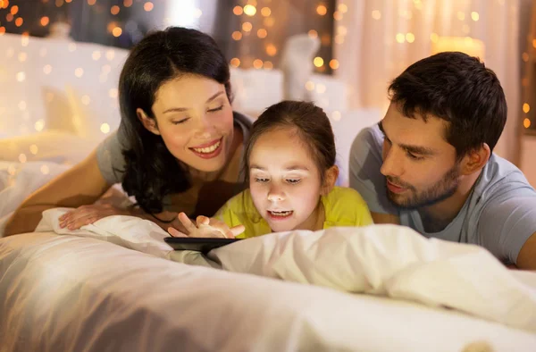 Familia con tableta pc en la cama por la noche en casa —  Fotos de Stock