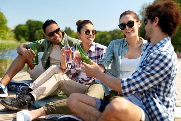 Vrienden drinken bier en cider op de pier van het meer — Stockfoto
