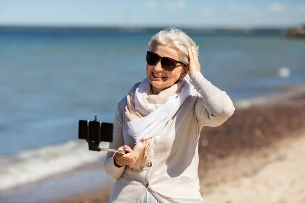 Femme âgée prenant selfie sur la plage — Photo