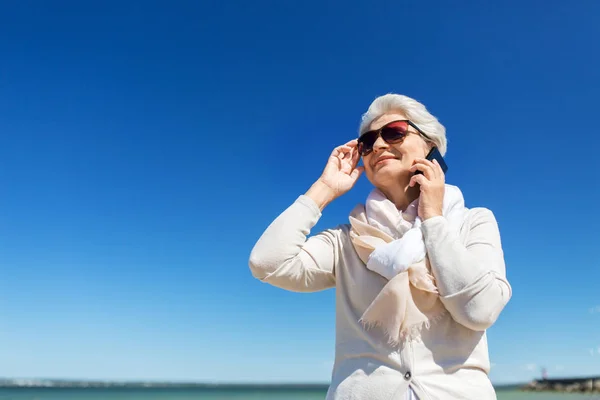 Donna anziana che chiama su smartphone sulla spiaggia — Foto Stock