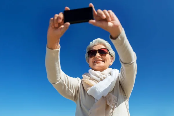 Mulher sênior tomando selfie por smartphone ao ar livre — Fotografia de Stock