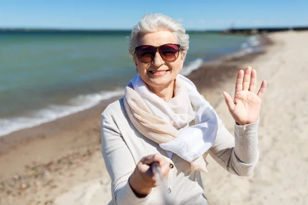 Vieille femme prendre selfie et agitant la main sur la plage — Photo
