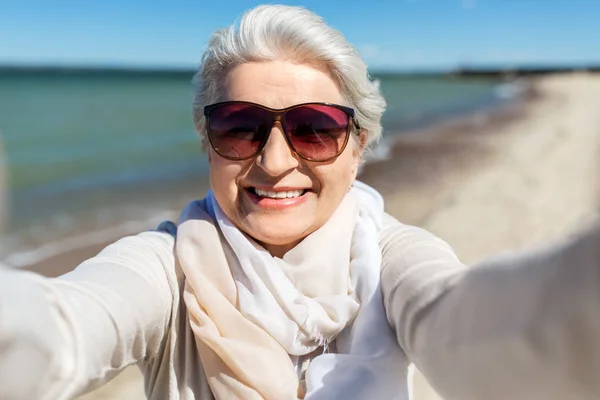 Senior femme en lunettes de soleil prendre selfie sur la plage — Photo