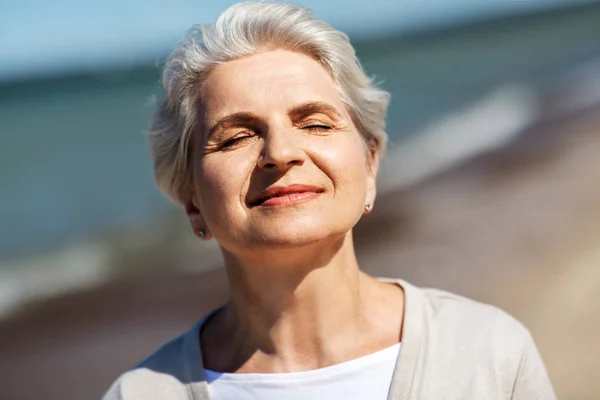 Porträtt av Senior Kvinna njuter sol på stranden — Stockfoto