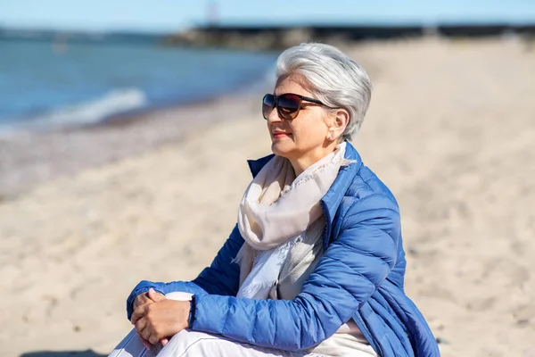 Heureuse femme âgée en veste sur la plage — Photo
