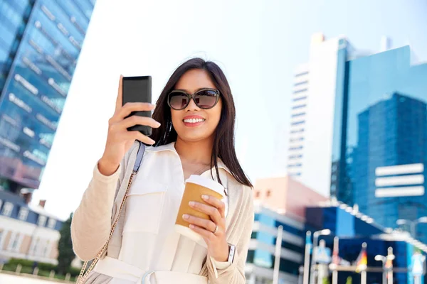 市内のスマートフォンとコーヒーで笑顔の女性 — ストック写真