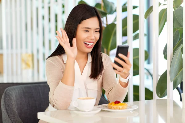 カフェでスマートフォンでビデオ通話をしている女性 — ストック写真