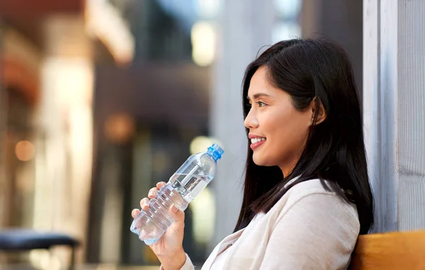 Mujer agua potable sentado en banco de madera de la ciudad — Foto de Stock