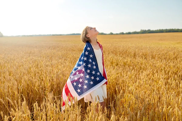 Menina feliz na bandeira americana no campo de cereais — Fotografia de Stock