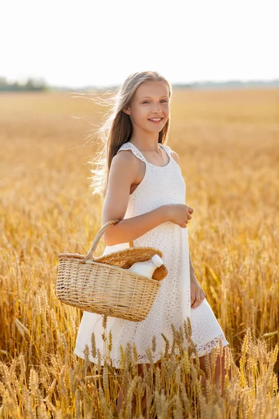 Ragazza con pane e latte in cesto sul campo di cereali — Foto Stock