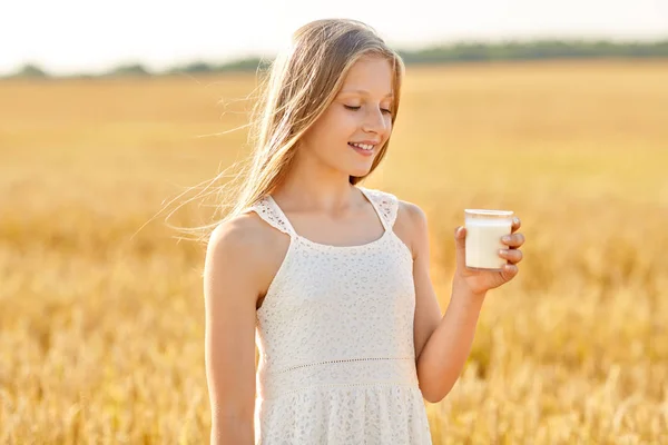 Chica feliz con vaso de leche en el campo de cereales — Foto de Stock