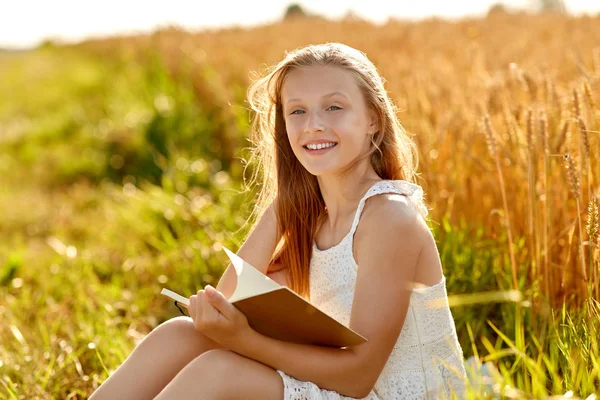 Usmívající se dívka čtení deníku na poli cereálie — Stock fotografie