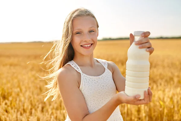 Menina feliz com garrafa de leite no campo de cereais — Fotografia de Stock