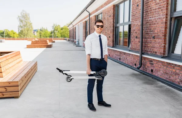 Uomo d'affari con scooter pieghevole sul tetto — Foto Stock