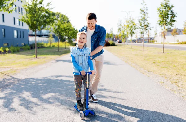 Gelukkig vader en zoontje paardrijden scooter in stad — Stockfoto