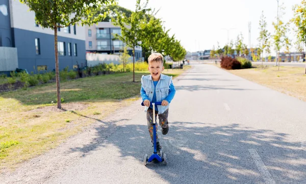 Gelukkig jongetje paardrijden scooter in stad — Stockfoto