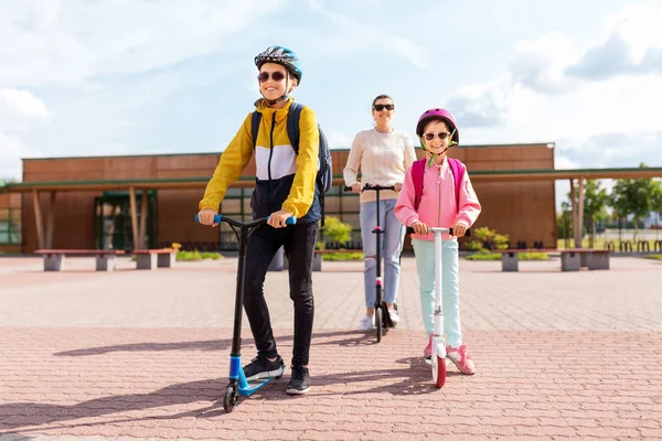 Bambini felici della scuola con la madre che guida scooter — Foto Stock