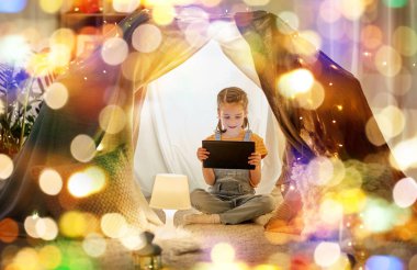 little girl with tablet pc in kids tent at home clipart