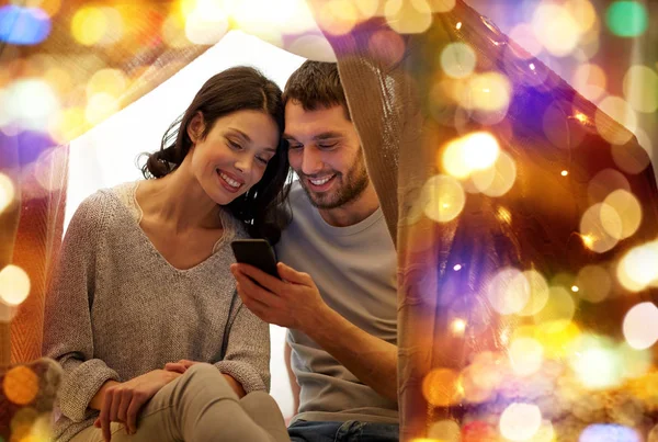 Glückliches Paar mit Smartphone im Kinderzelt zu Hause — Stockfoto