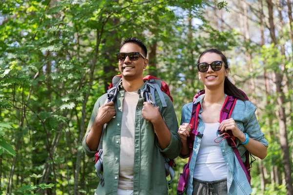 Casal de raça mista com mochilas caminhadas na floresta — Fotografia de Stock