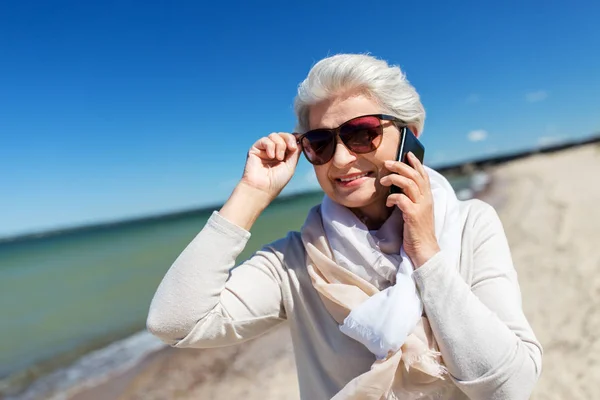 Starsza kobieta dzwoniąc na smartfonie na plaży — Zdjęcie stockowe