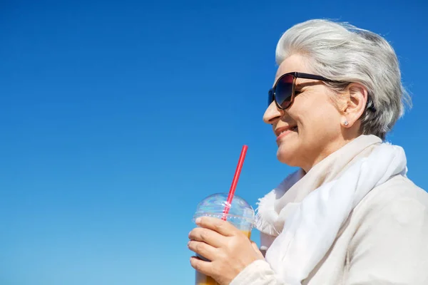 Senior femme boire du jus d'orange à l'extérieur — Photo