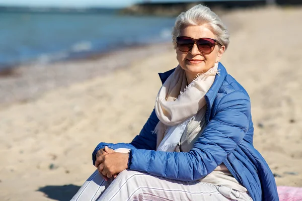 Plajda ceket mutlu yaşlı kadın — Stok fotoğraf