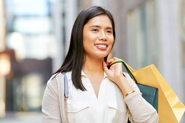 Aziatische vrouw met boodschappentassen in de stad — Stockfoto