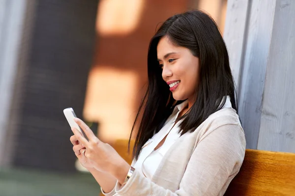 Mulher asiática usando smartphone sentado no banco — Fotografia de Stock